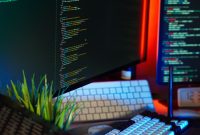 A vibrant workspace showing computer monitors with code, keyboard, and tech accessories.