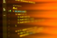 Vibrant, motion-blurred view of programming code on a computer screen with an abstract orange glow.